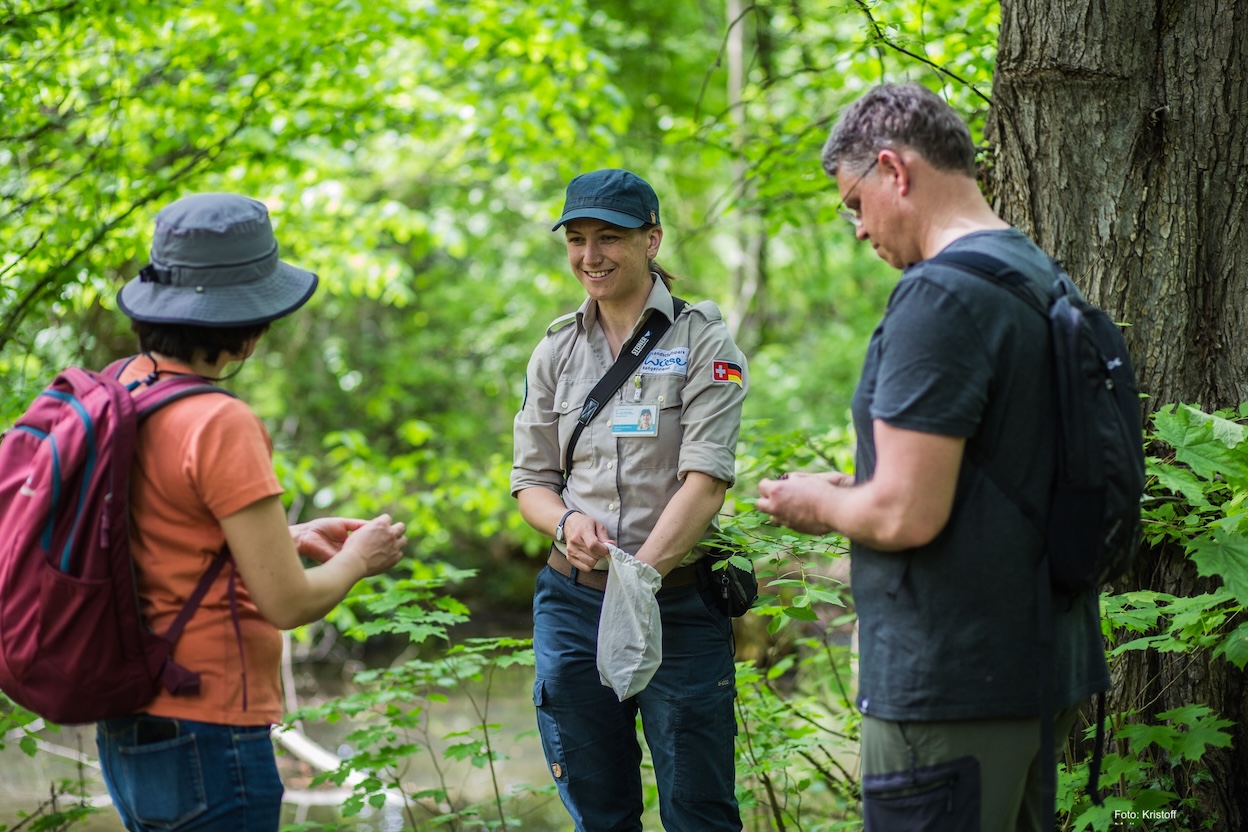Rangerin im Landschaftspark Wiese im Gespräch mit zwei Personen
